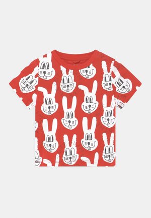 Maglietta rossa a maniche corte, decorata con facce di coniglietto animato bianche in diverse posizioni ed espressioni, stampate su tutta la stoffa.