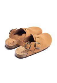 Bruine suède klompen met twee verstelbare riempjes, zilveren gespen en een kurken voetbed. Voorzien van een antisliprubberen zool en een gladde binnenkant.