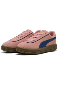 Zapatillas de gamuza rosa con una franja lateral azul y acentos dorados en el logo. Presentan una suela de goma y un diseño clásico con cordones.