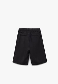 Pantalones cortos negros con una textura suave, que cuentan con una cinturilla elástica y dos bolsillos traseros. Diseño sencillo, sin patrones ni acentos visibles.