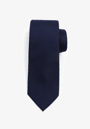 Marineblauwe stropdas met een gestructureerde, geweven afwerking en een taps toelopende punt. Het materiaal lijkt zacht maar toch duurzaam, geschikt voor formele gelegenheden.