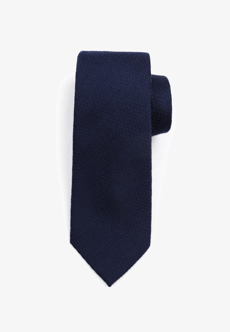 Marineblauwe stropdas met een gestructureerde, geweven afwerking en een taps toelopende punt. Het materiaal lijkt zacht maar toch duurzaam, geschikt voor formele gelegenheden.