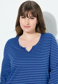 Maglietta a manica lunga a righe blu con scollatura a V. Presenta righe alternate di azzurro e blu scuro. Tessuto morbido e design casual.