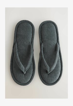 Graue Textilschuhe mit einer weichen, plüschigen Oberfläche, ausgestattet mit einem Zehensteg-Design und abgerundeten Kanten, auf einem hellen Hintergrund platziert.