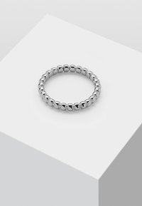 Sølvfarget perle-ring med avrundede, polerte perler i et ensartet mønster, plassert på en minimalistisch hvit overflate.