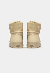 Bottes de cheville beige en toile, avec un col rembourré et un logo en relief sur le talon. Semelle en caoutchouc texturé avec motifs de grip.