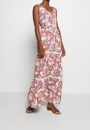Woman wearing sleeveless V-neck white maxi dress with pink, orange, and gray paisley pattern, paired with brown open-toe block-heeled sandals.