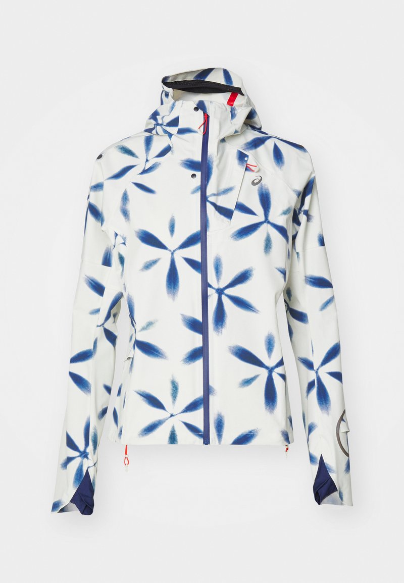 Damenjacke mit weißem Grund und blauen Blumenmustern. Sie verfügt über einen Reißverschluss, eine Kapuze und kontrastierende marineblaue Akzente an den Ärmeln.