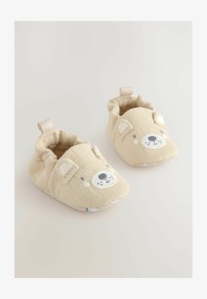 Bézs babacipő maci arcmintával; puha anyagból készült, lekerekített formájú, és hátul pánttal az egyszerű felvételhez.