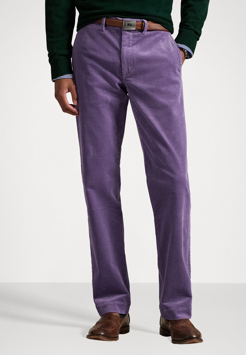 Paars corduroy broek met verticale ribbels, met een recht model, zijzakken en een bruine leren riem. Bruine schoenen maken de look compleet.