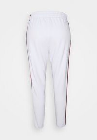 Bílé sportovní kalhoty s úzkým střihem, s vínovými bočními pruhy a elastickým pasem pro pohodlí. Hladká textura bez viditelných vzorů.