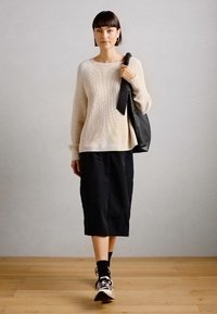 Knit cream sweater, black midi skirt, black bag, and sneakers. Sweater has ribbed texture, softer colors, and a relaxed fit.