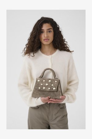 Szara zamszowa torebka o wyraźnym kształcie, z metalowymi ćwiekami na przodzie i krótkim uchwytem. Stylizowana z kościelnym swetrem.