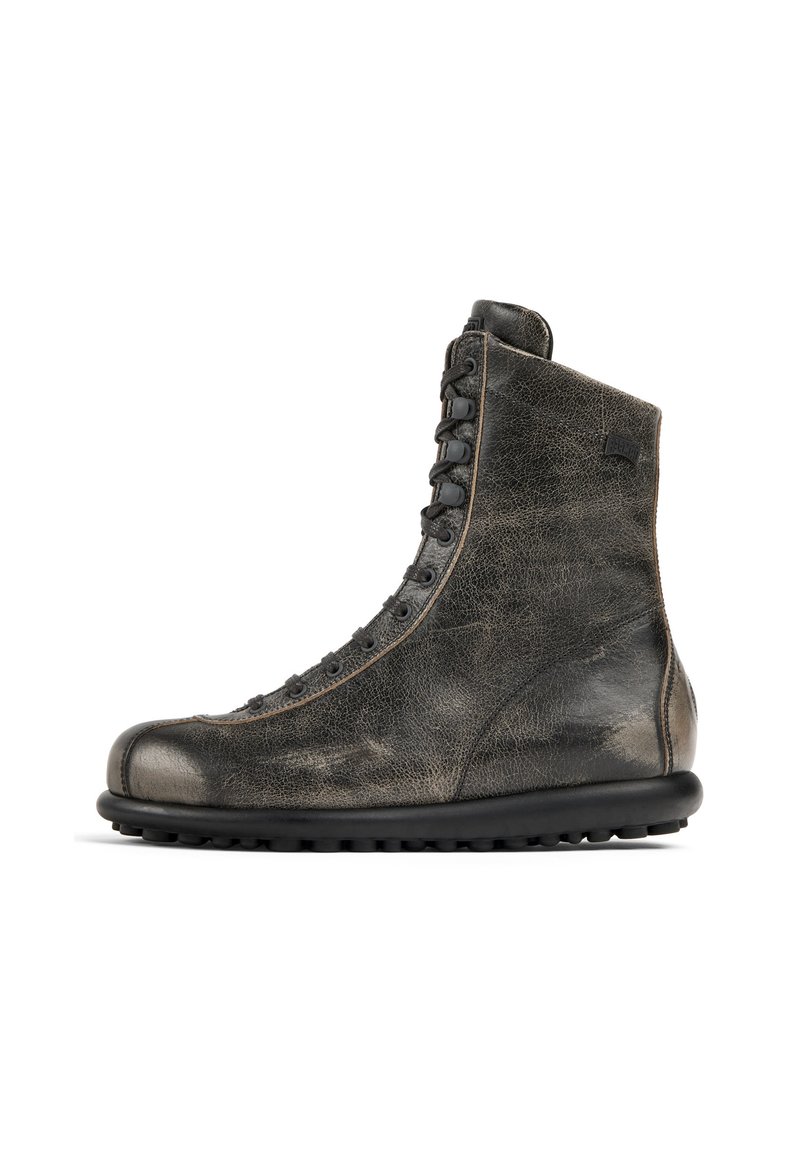 Bottines en cuir noir avec une finition texturée, bout arrondi et sept paires d'œillets. Dotées d'une semelle en caoutchouc noir avec une texture antidérapante.