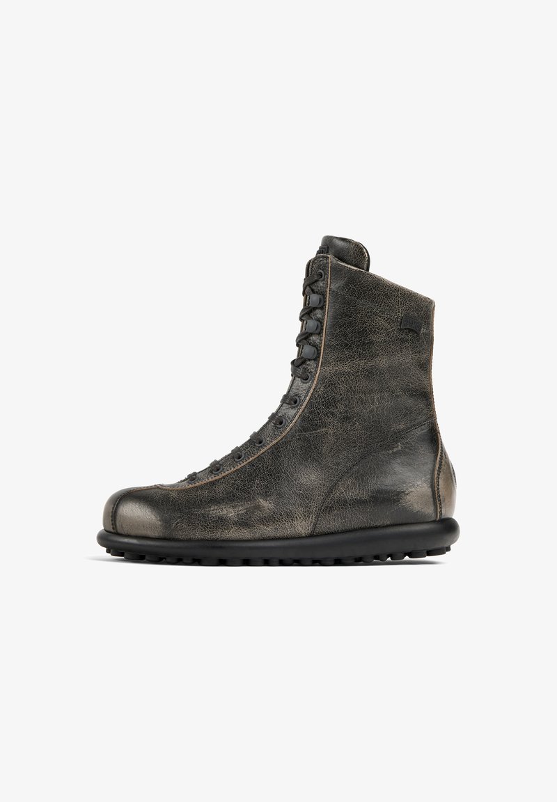 Bottines en cuir noir avec une finition texturée, bout arrondi et sept paires d'œillets. Dotées d'une semelle en caoutchouc noir avec une texture antidérapante.