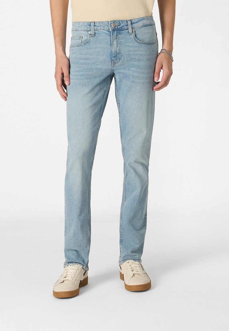 Jeans de denim azul claro con un corte recto, que cuentan con un cierre de botón, cinco bolsillos y un ligero desvanecimiento para añadir textura.