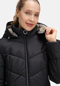 Czarna kurtka puchowa z zamkiem z przodu, kapturem z futerkiem syntetycznym i pikowanym wzorem. Lekka i ocieplona dla zapewnienia ciepła.