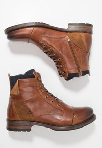 Bottines en cuir marron avec un bout arrondi, des panneaux texturés, un laçage à l'avant, une fermeture éclair et un talon en bois. Accents en daim beige.