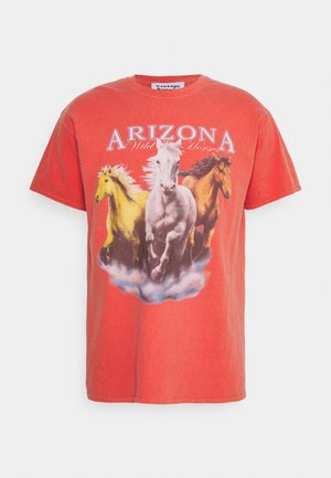 T-shirt rouge corail avec trois chevaux au galop en jaune, blanc et marron, avec le texte "ARIZONA Wild Horses" au-dessus.