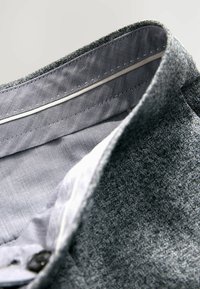 Grau strukturierten Stoff mit einem glatten, hellen Kragenfutter mit Steppdetails und einem Knopfverschluss.