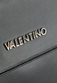 Portafoglio in pelle nera con superficie testurizzata e logo "VALENTINO" in tono oro ben visibile sulla parte anteriore.