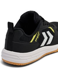 Schwarzer Sportschuh mit Mesh-Obermaterial, weißen Akzenten und flexiblem Gummisohlen. Verfügt über ein gelbes Logo und eine Lasche an der Ferse.