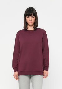 Bordo oversized mikina s kulatým výstřihem, spadlými rameny a dlouhými rukávy. Vyrobena z měkké tkaniny s hladkým povrchem.