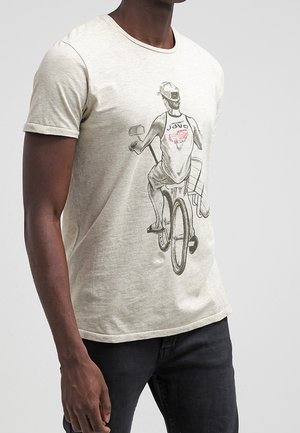 Camiseta de manga corta de color beige claro, hecha de una mezcla de algodón, que presenta un estampado gráfico de un ciclista en una bicicleta con una mochila en la espalda.