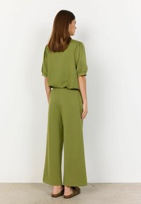 Olivově zelený dvoudílný outfit skládající se z krátkého rukávového volného topu a širokých kalhot po kotníky, vyrobený z měkké strukturované látky.