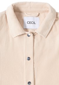 Lichtbeige corduroy shirt met een gestructureerd patroon, knoopsluiting en een kraagnek. Voorzien van een prominent merkembleem.