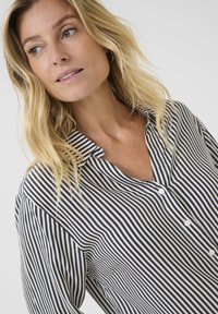 Camicia a righe blu navy e bianca, realizzata in tessuto leggero, con colletto e patta con piccoli bottoni bianchi.