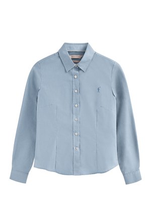 Chemise à manches longues bleu clair avec un devant boutonné, un col et des poches latérales. Présente un petit logo brodé sur la poitrine. Texture de tissu lisse.