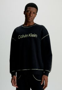 Černá mikina s logem Calvin Klein v světlezelené barvě, s kontrastním šitím, kulatým výstřihem a dlouhými rukávy.