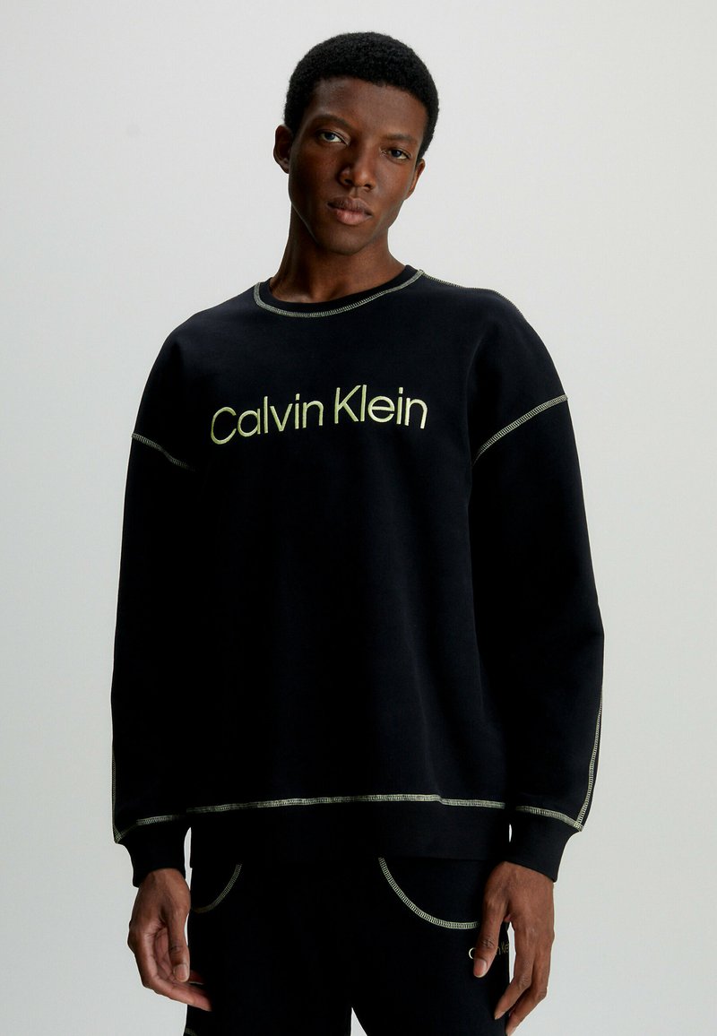 Černá mikina s logem Calvin Klein v světlezelené barvě, s kontrastním šitím, kulatým výstřihem a dlouhými rukávy.
