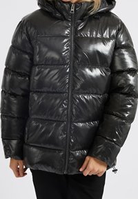 Černá péřová bunda s lesklým povrchem. Disponuje zipem v přední části, kapucí a polstrovanými částmi pro izolaci. Nastavitelná šňůrka na spodním lemu.