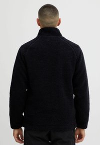 Donkerblauwe fleecetop met een hoge kraag, gestructureerd oppervlak en lange mouwen. Heeft een ontspannen pasvorm en een rechte zoom.