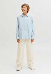 Světle modrá pruhovaná košile s knoflíky a kapsou, v kombinaci se smetanovými širokými kalhotami a bílými teniskami. Jednoduchý design a volný střih.