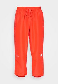 Klarröda byxor med elastisk midja och dragsko, raka ben, liten vit logotyp på vänster ben och subtil textdetalj på höger lår.