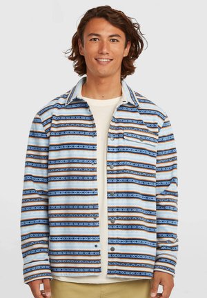 Skjorte med knapper i ternet mønster i blå, brun og creme, med blød tekstur, lange ærmer og en enkelt brystlomme med lukning i metal.