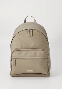 Beige stofrygsæk med afrundet top, to lynlåslommer og en forlommer. Har sølvfarvet hardware og en mærketag.