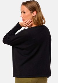 Schwarzer, übergroßer Strickpullover mit langen Ärmeln, gerippten Bündchen und einem lässigen Schnitt. Der Stoff wirkt weich und strukturiert und eignet sich gut für die Freizeit.