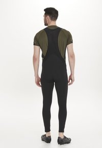 Svarta cykelbyxor med bib och en olivgrön kortärmad topp, med ett mesh bakpanel och en åtsittande design för ökad komfort och rörlighet.