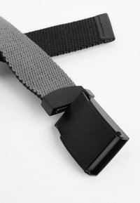 Belt réglable avec une sangle en tissu tissé gris et une boucle en métal noir mat de forme rectangulaire.