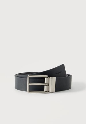 Cintura in pelle nera con fibbia in metallo argentato e logo Calvin Klein stampato sulla fascia e sulla fibbia.