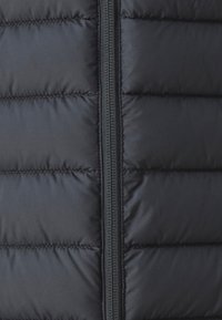 Svart puffjacka med vertikal dragkedja, quiltad textur med jämnt fördelade sektioner och slät tygfinish.