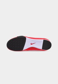 Σόλα κόκκινου παπουτσιού Nike με μαύρο καουτσούκ στη φτέρνα και τα δάχτυλα, λευκή περιοχή μέσης σόλας με κόκκινο λογότυπο Nike swoosh.