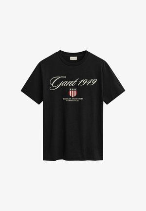 T-shirt in cotone nero con maniche corte, caratterizzata da un logo bianco in corsivo "Gant 1949" e una grafica a forma di scudo rossa con stelle sottostante.