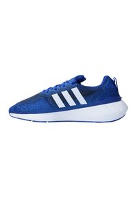 Zapatillas deportivas azules con parte superior de punto, con el logotipo de tres franjas blancas, cordones planos y suela gruesa blanca con detalles azules.