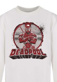 Witte longsleeve shirt met een graphic van Deadpool in rood en grijs, met spetterdetails en vetgedrukte tekst "DEADPOOL" eronder.