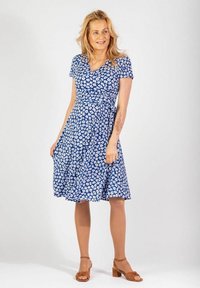 Niebieska sukienka kopertowa z krótkimi rękawami, z białym wzorem w kwiaty. Lekka tkanina z dopasowanym w pasie, delikatnie rozszerzająca się do kolan.